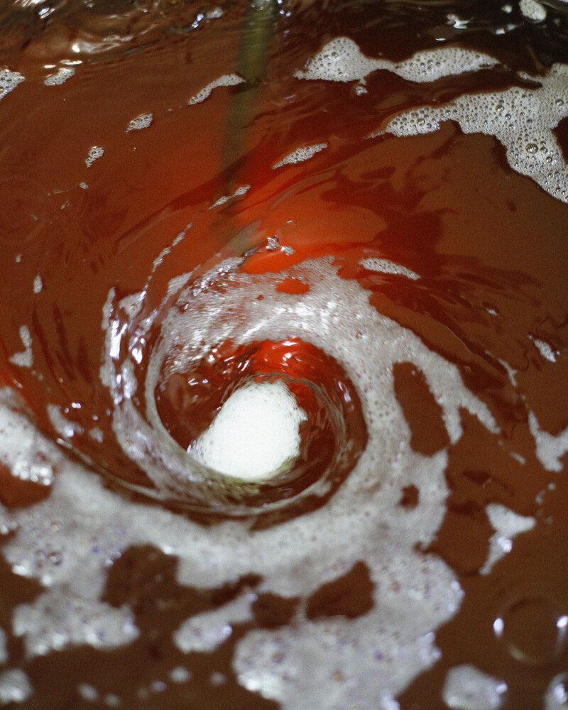 اللون الياقوتي العميق لتركيز العطر الثمين وهو يمتزج داخل خزانات مصنع أمواج